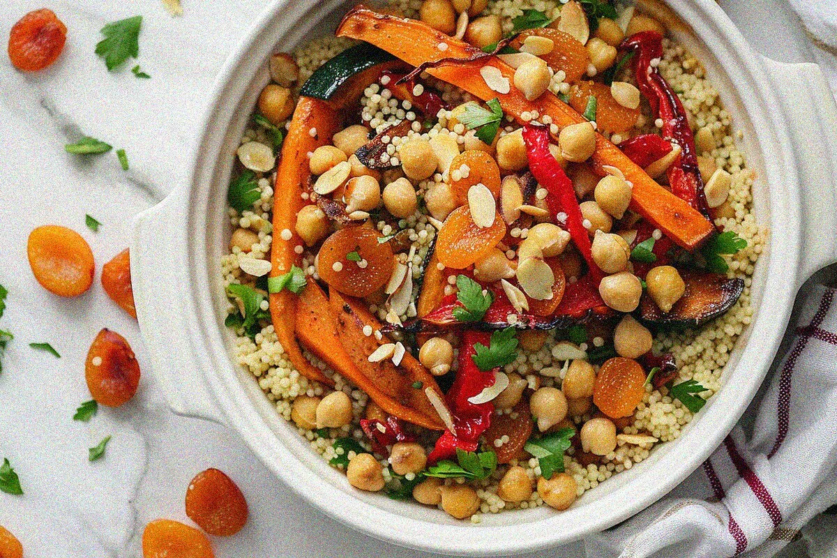 Beautifully plated moroccan couscous recipes with roasted vegetables, chickpeas, and almonds in white bowl
