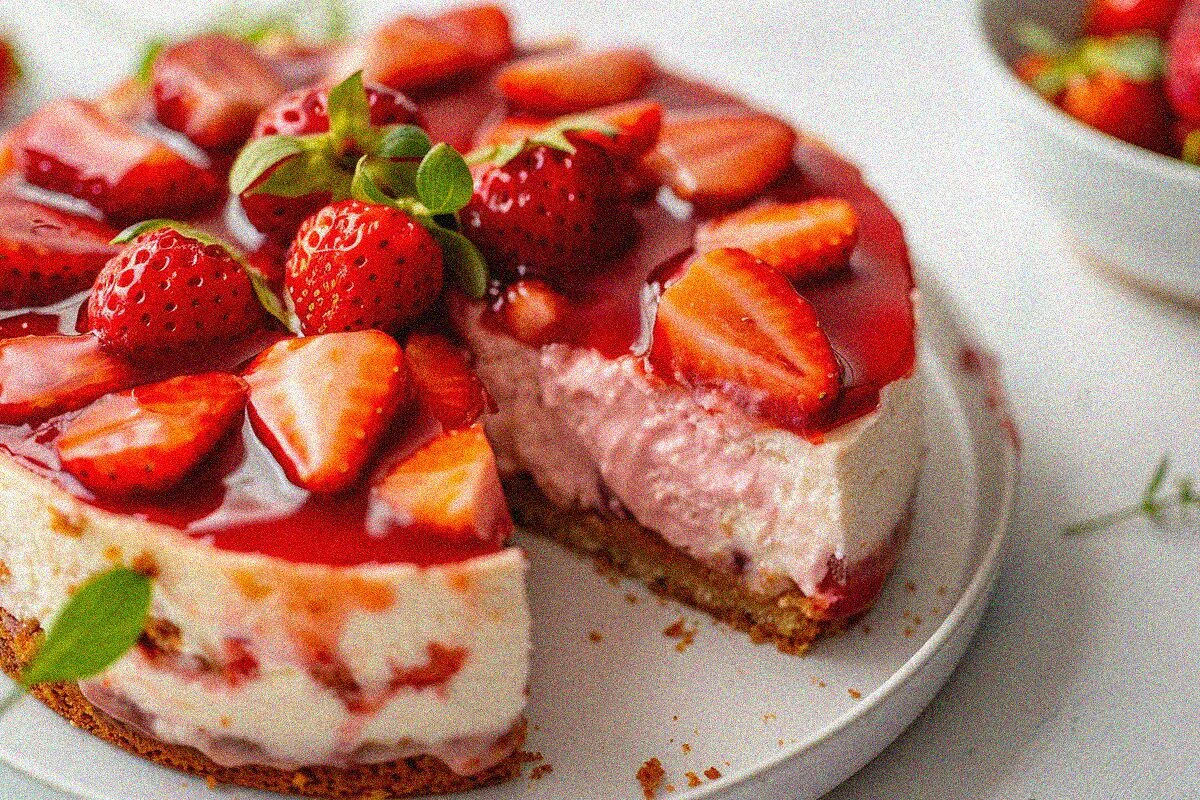 Slice of creamy strawberry cheese cake with fresh strawberry topping and glossy glaze, showing layers and texture